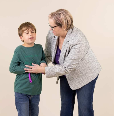 An adult helping young boy standing with his eyes closed