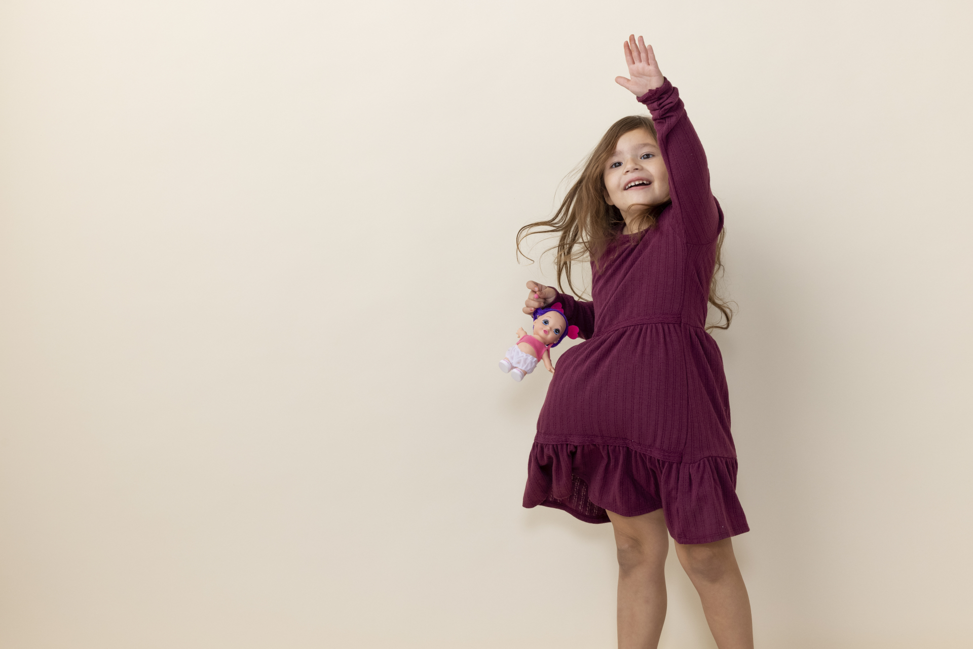 Little girl in red dress, reaching high with one hand.