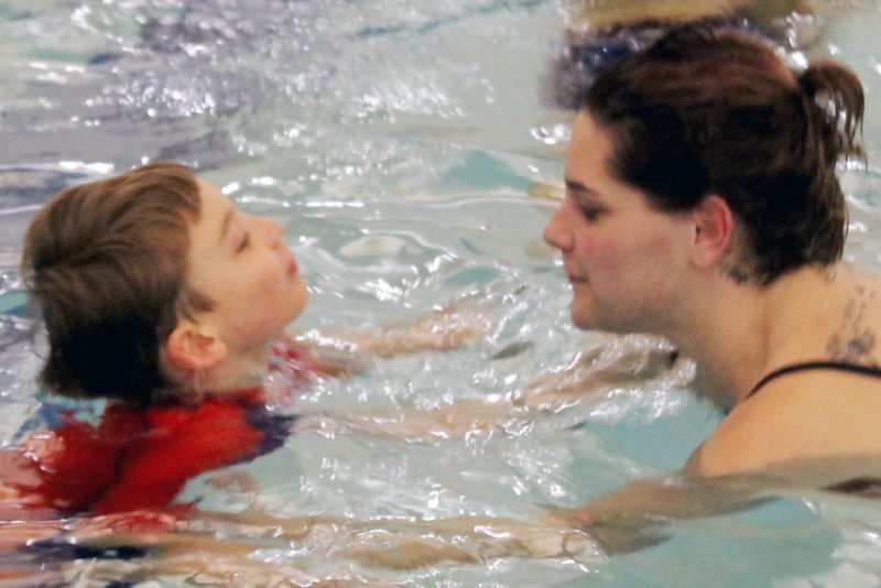 Boy learning to swim with teacher