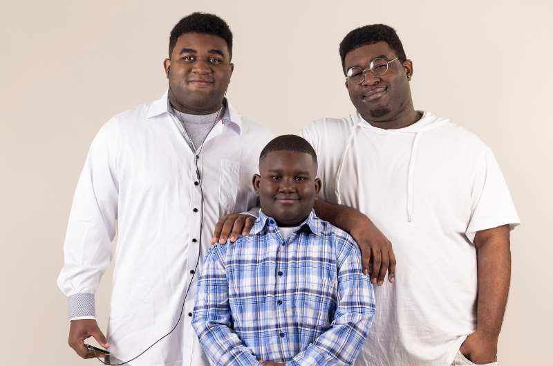 Two teen boys smiling with younger boy