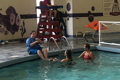 young boy with autism getting swim instructions in a pool