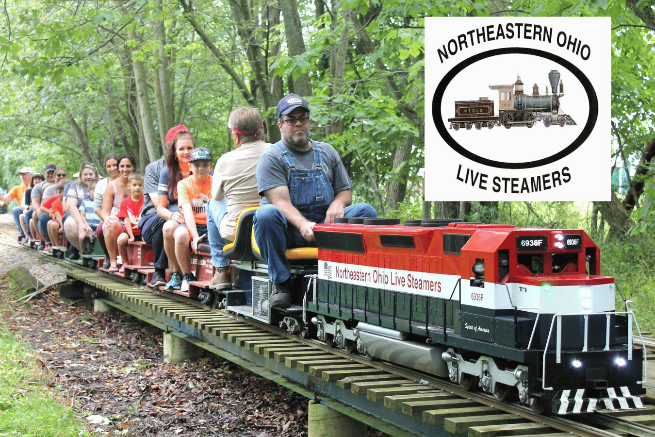 People ride a miniature train operated by the Northeastern Ohio Live Steamers along an elevated track through a wooded area. The Northeastern Ohio Live Steamers logo appears in the upper-right corner.